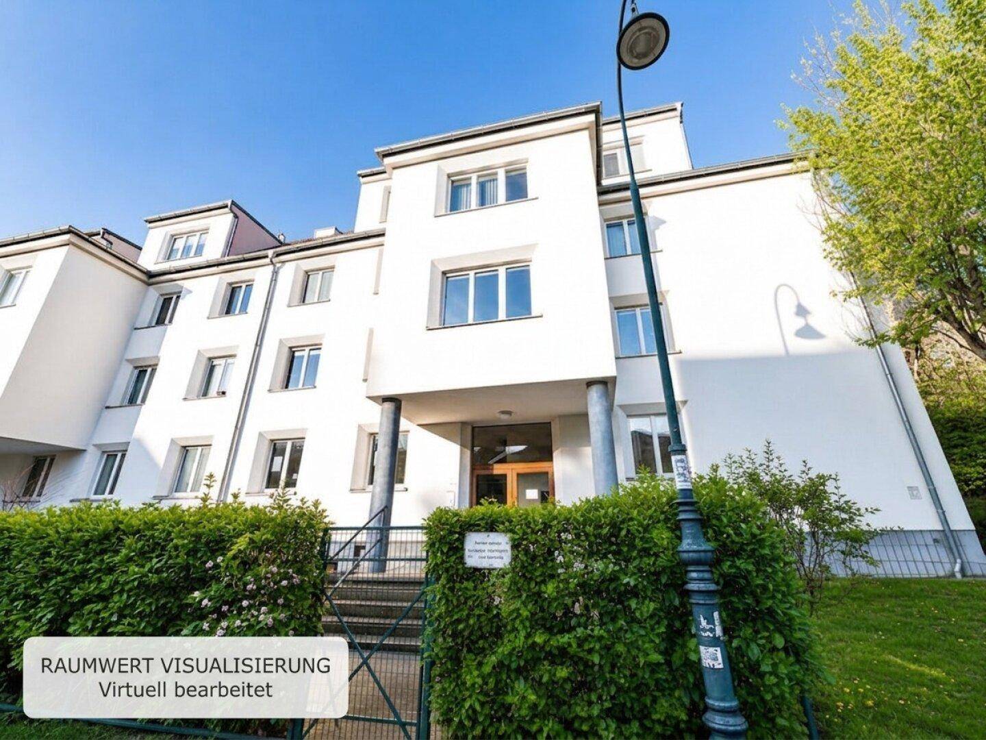 Mehrfamilienhaus mit weißer Fassade, vielen Fenstern und gepflegter Hecke im Vordergrund.