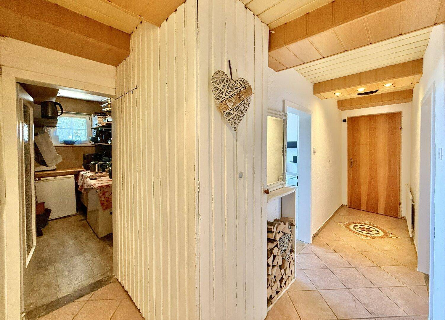 Eingangsbereich mit Holzverkleidung, Fliesenboden und dekorativer Holzablage.