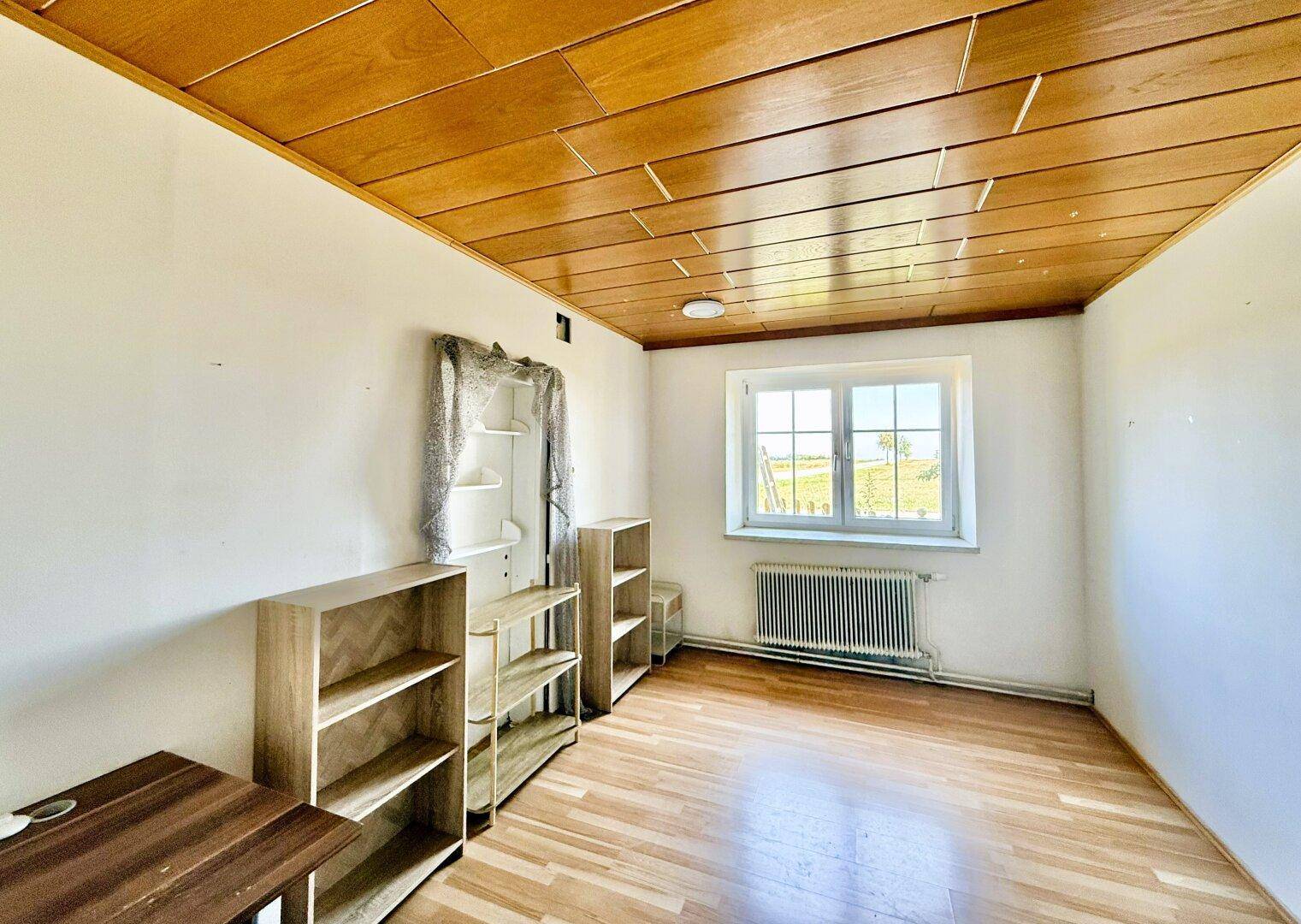 Heller Raum mit Holzfußboden, Holzdecke und Blick auf die Landschaft.