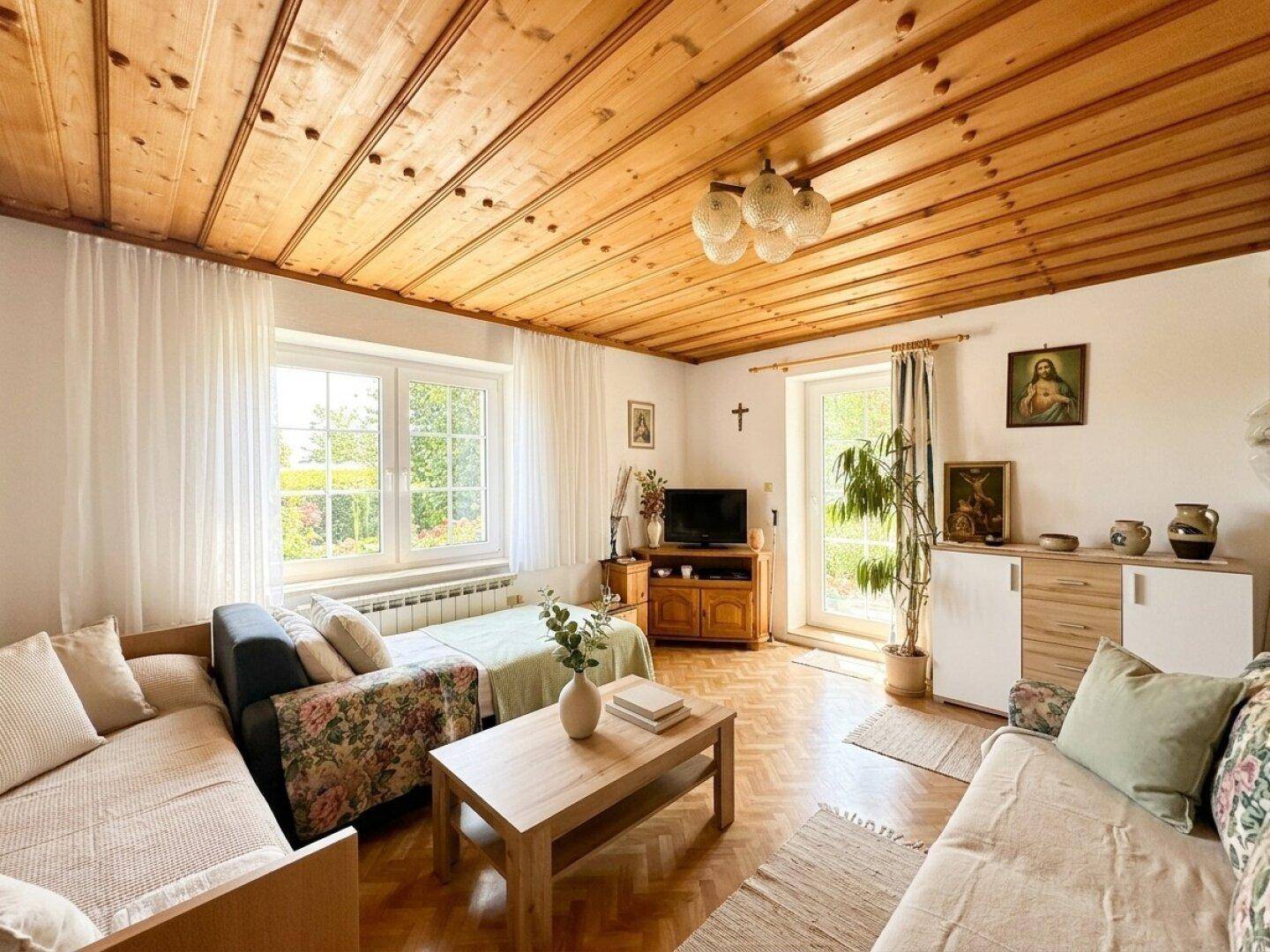 Helles Wohnzimmer mit Sofas, Couchtisch, Holzfußboden und Holzdeckenverkleidung.