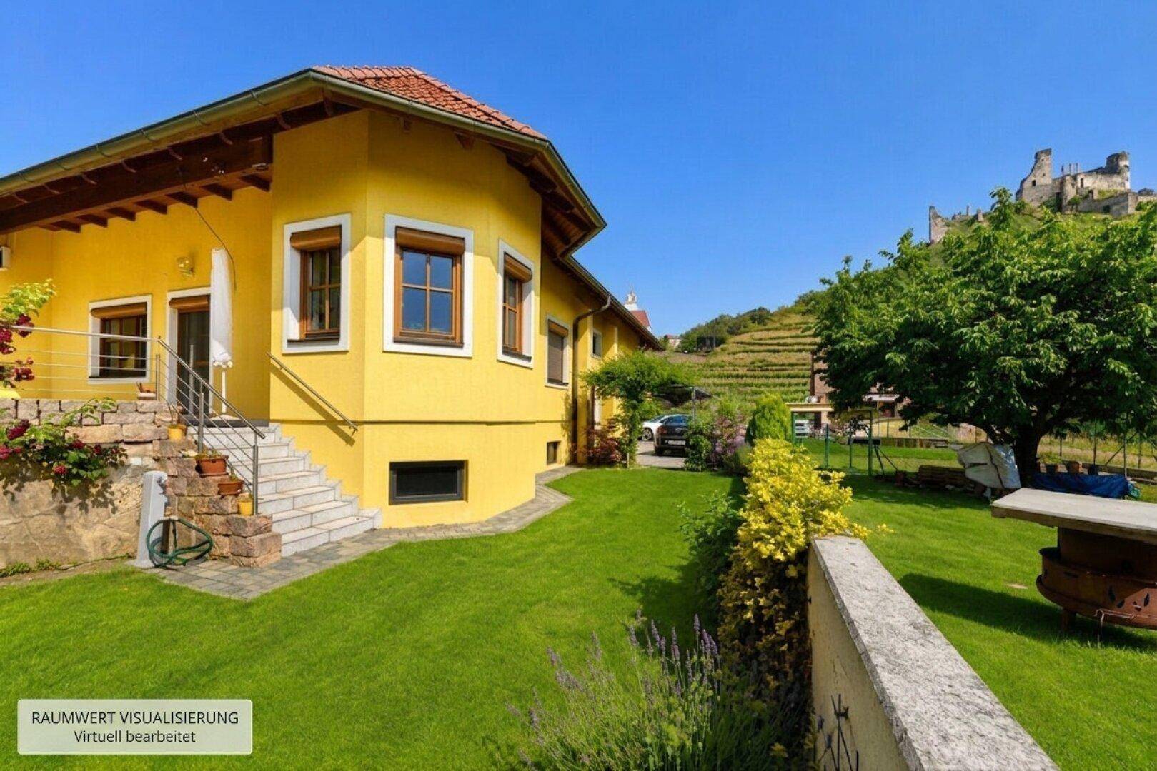 Gelbes Haus mit gepflegtem Garten, Außentreppe und weitem Blick auf Weinberge und eine Burgruine.