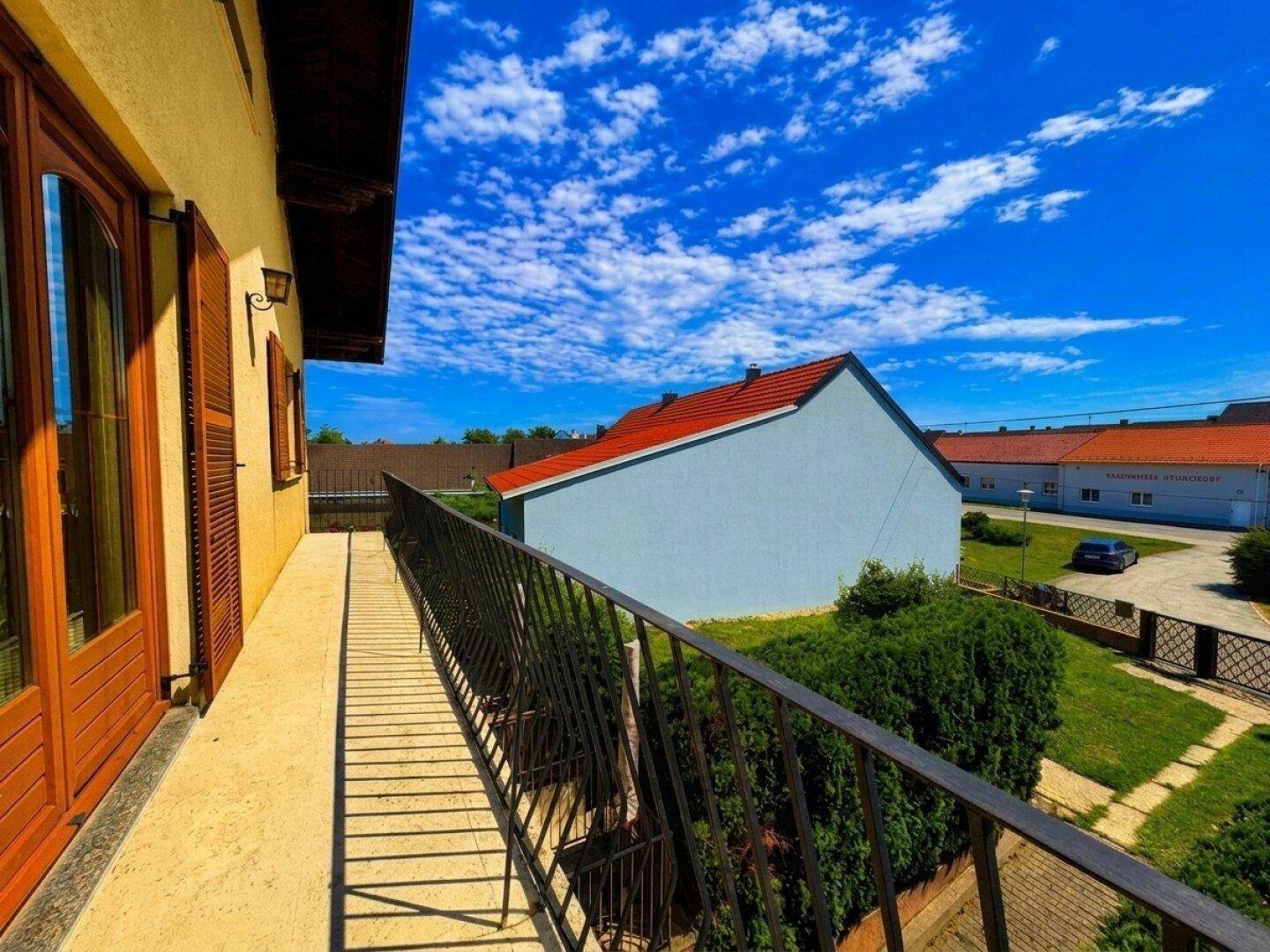 Blick vom Balkon auf die Umgebung mit weiteren Häusern und einem geparkten Auto.