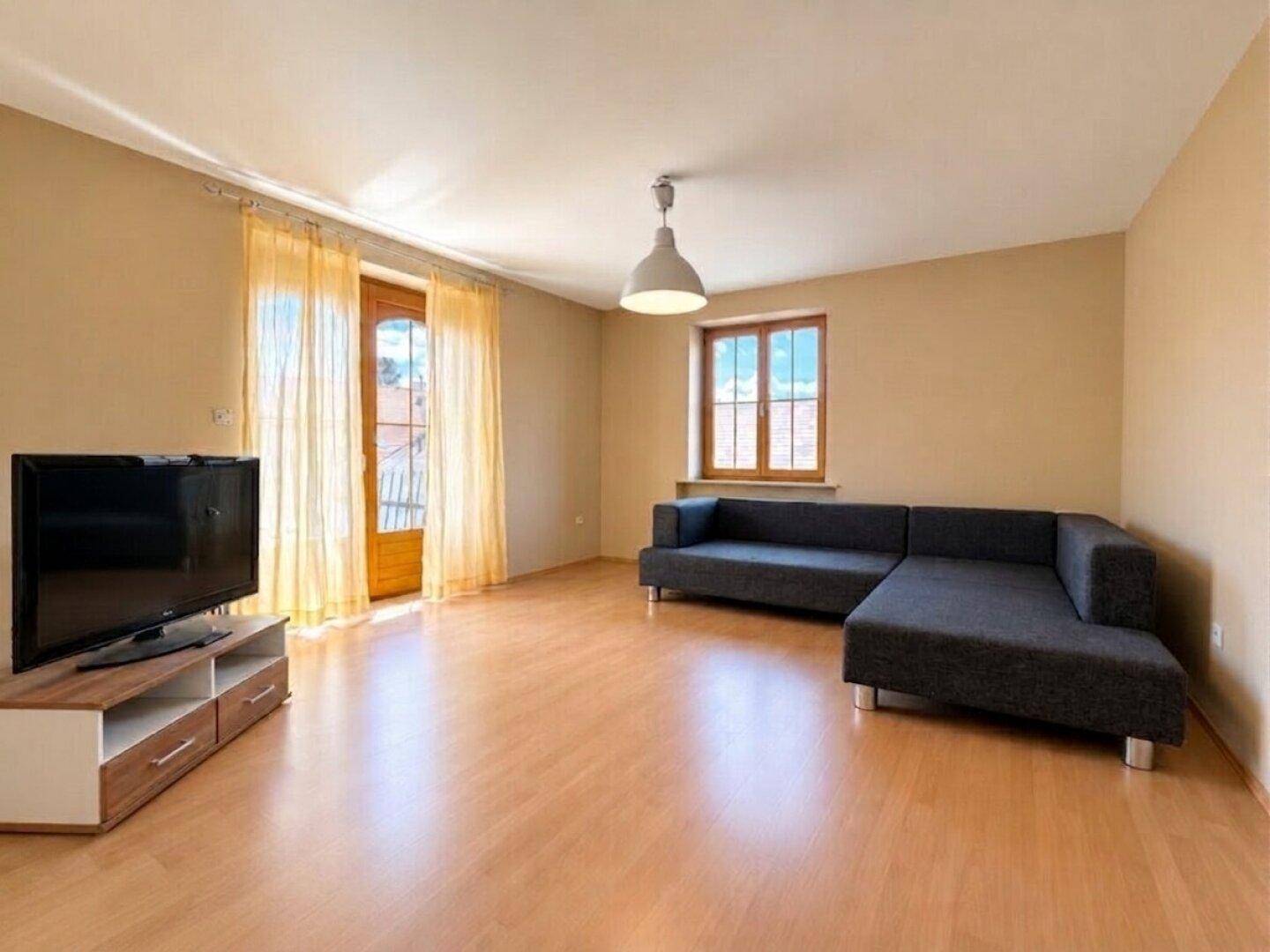 Helles Wohnzimmer mit Parkettboden, modernem Sofa und Zugang zum Balkon.