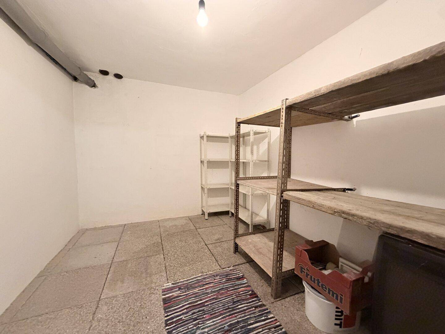 Praktischer Abstellraum im Keller mit Regalen für zusätzlichen Stauraum und Fliesenboden.