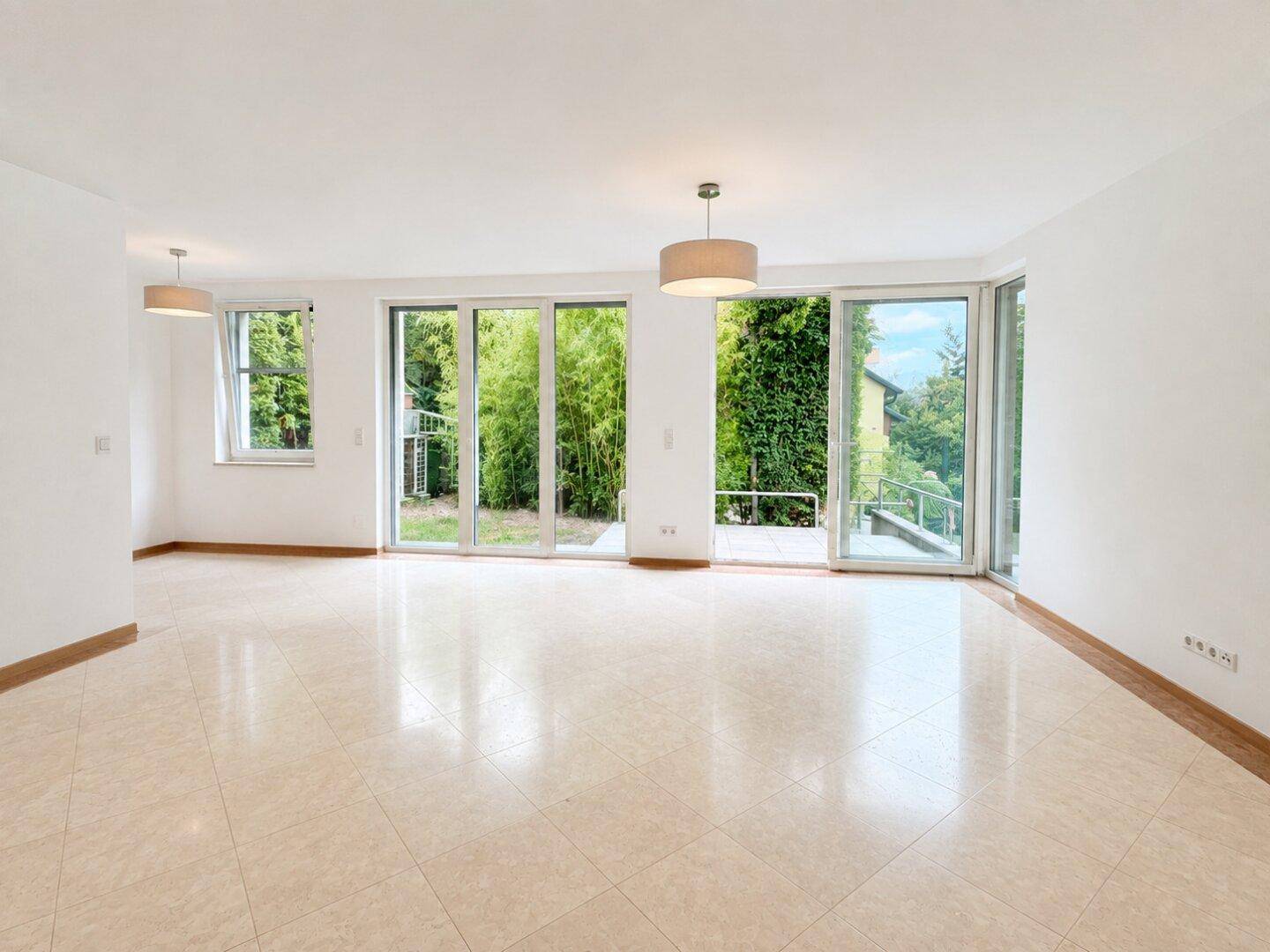Geräumiges Wohn-Esszimmer mit großen Fenstern, die viel Tageslicht hereinlassen und Blick ins Grüne bieten.