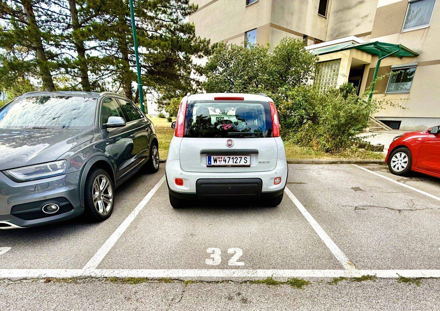 Außenparkplatz mit markierten Stellplätzen vor dem Wohngebäude.