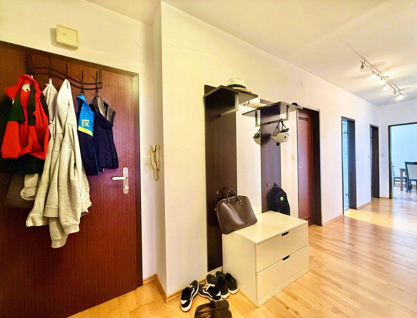 Eingangsbereich mit Garderobe, Schuhablage und hellem Holzfußboden.