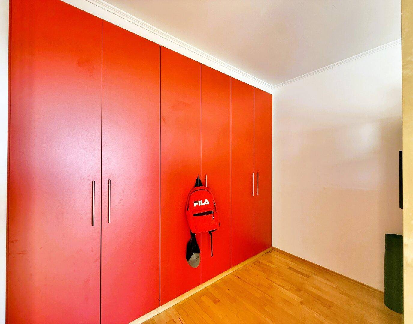 Zimmer mit auffälligen roten Einbauschränken, die viel Stauraum bieten.