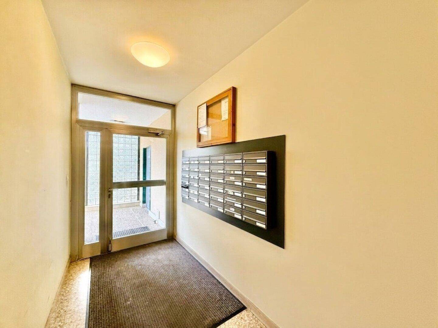 Eingangsbereich des Gebäudes mit Briefkästen und einer Glastür.