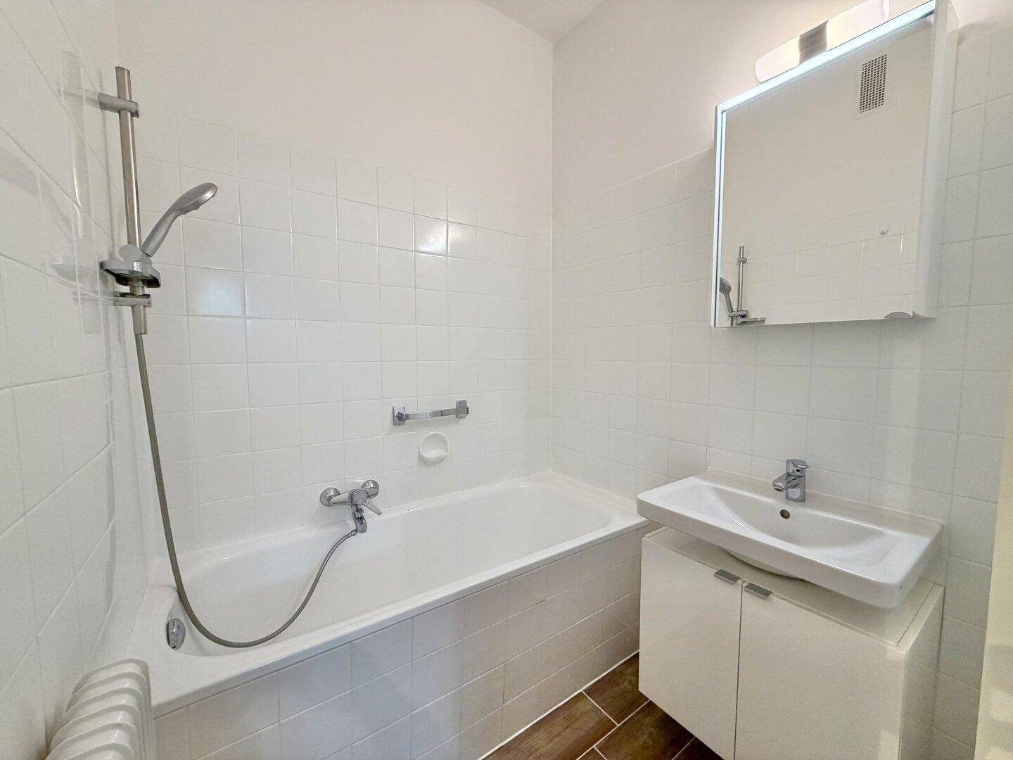 Badezimmer mit Badewanne, integrierter Dusche, Waschbecken und weißen Fliesen.