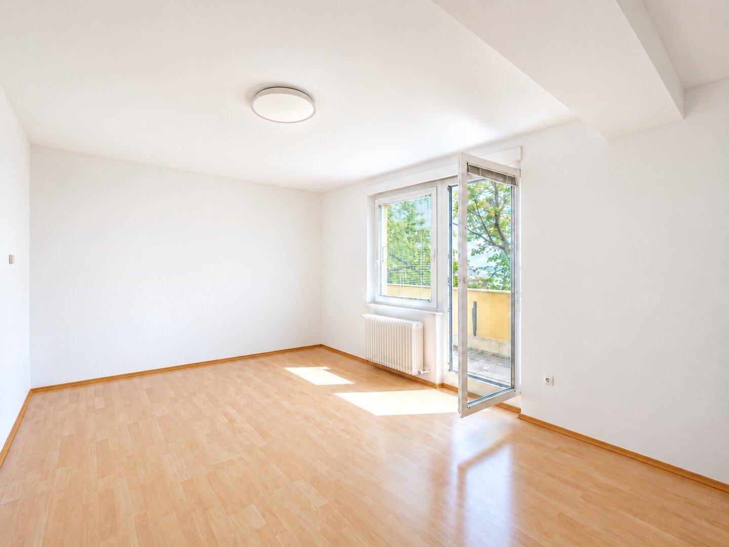 Heller, leerer Raum mit Parkettboden und Zugang zu einem Balkon, ideal für individuelle Gestaltung.