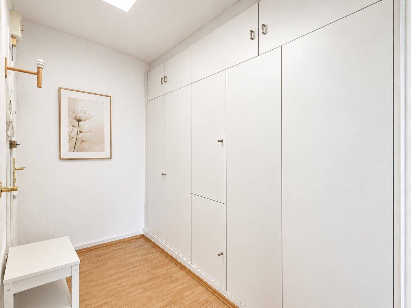 Flur mit praktischen Einbauschränken und hellem Holzfußboden für Stauraum.