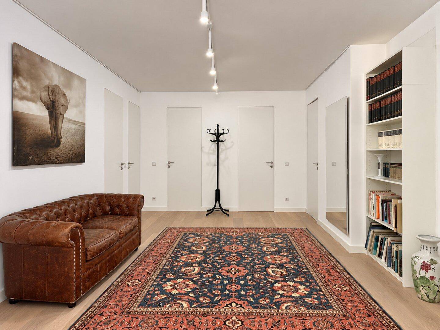 Geräumiger Flur mit Holzboden, Bücherregal und einem Chesterfield-Sofa, einladend gestaltet.