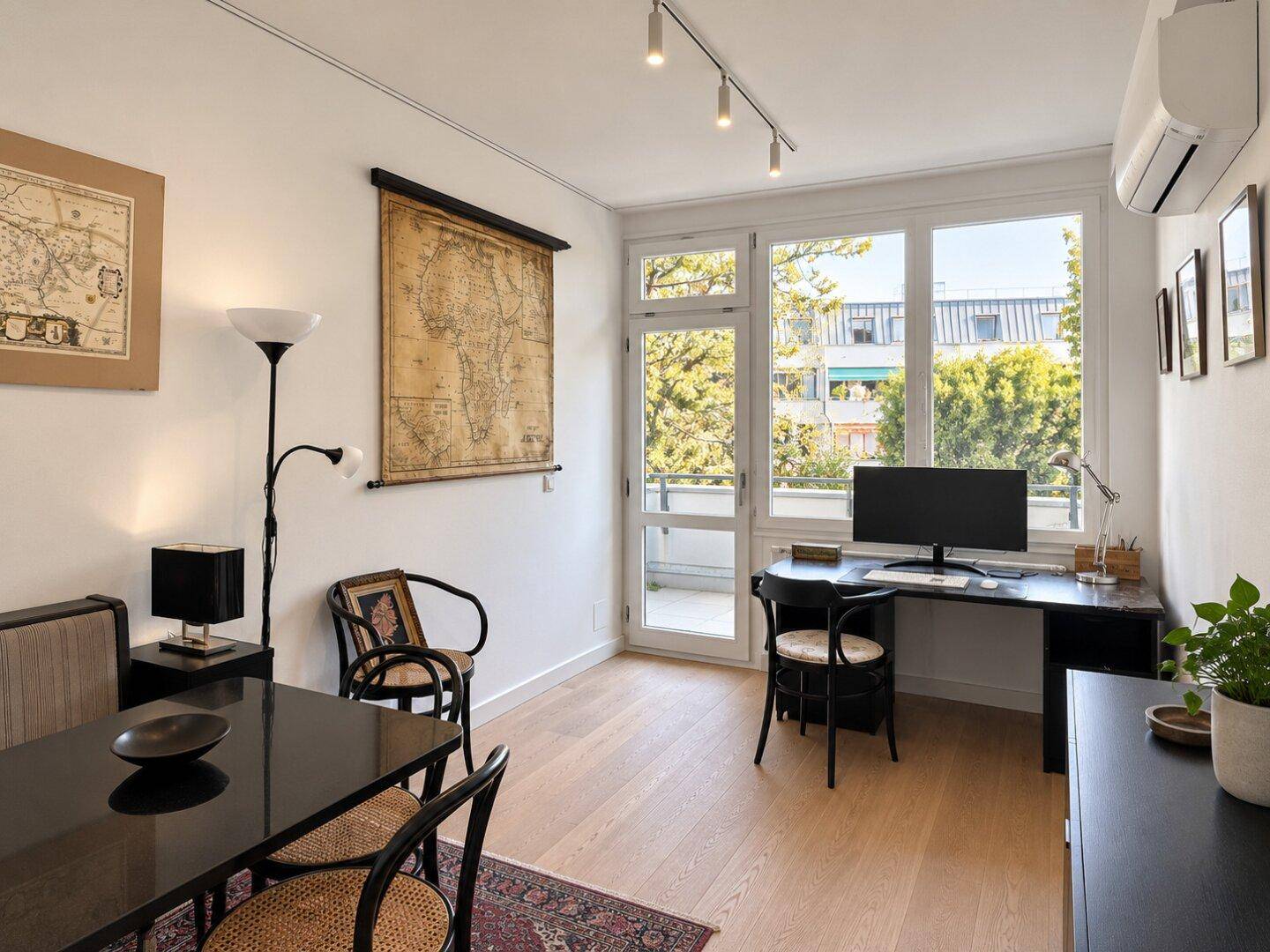 Arbeitsbereich mit Schreibtisch, dunklen Möbeln und Zugang zu einem Balkon, hell und funktional.