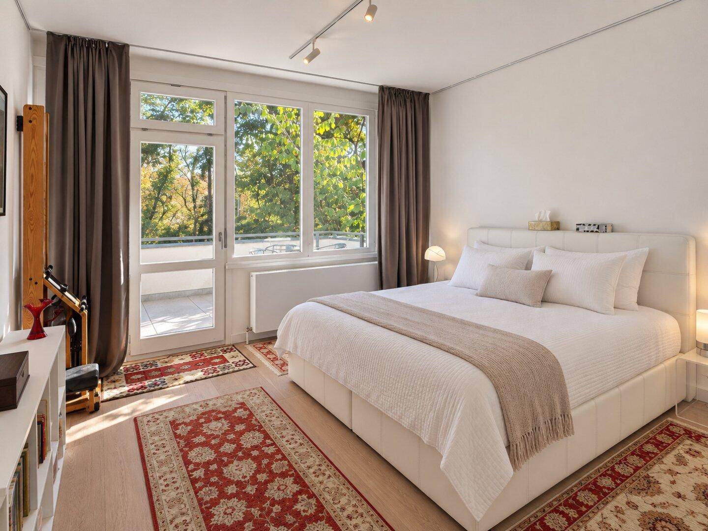 Helles Schlafzimmer mit großem Doppelbett, Holzboden und Zugang zum Balkon, sehr einladend.