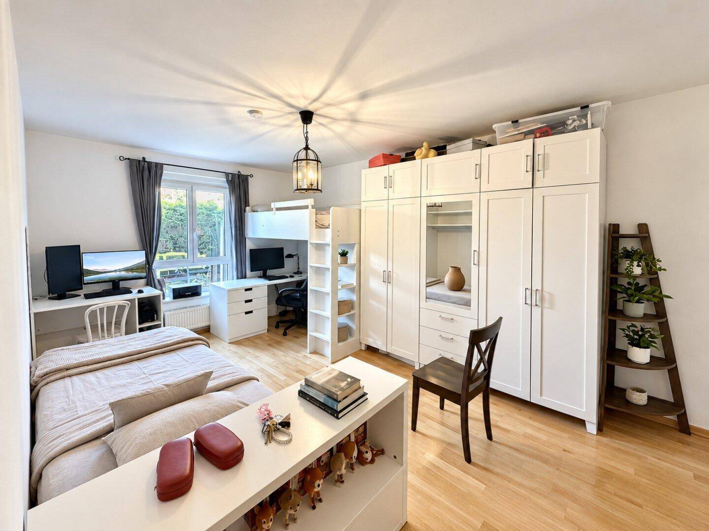 Helles Schlafzimmer mit Einzelbett, Schreibtischbereich und großen weißen Kleiderschränken.