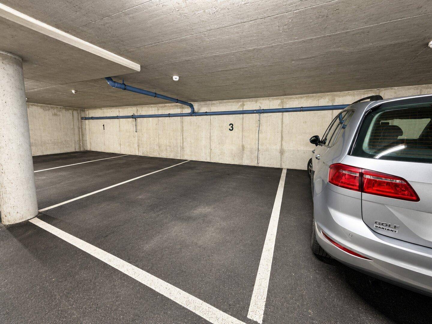 Tiefgarage mit markierten Stellplätzen und einem geparkten Fahrzeug.