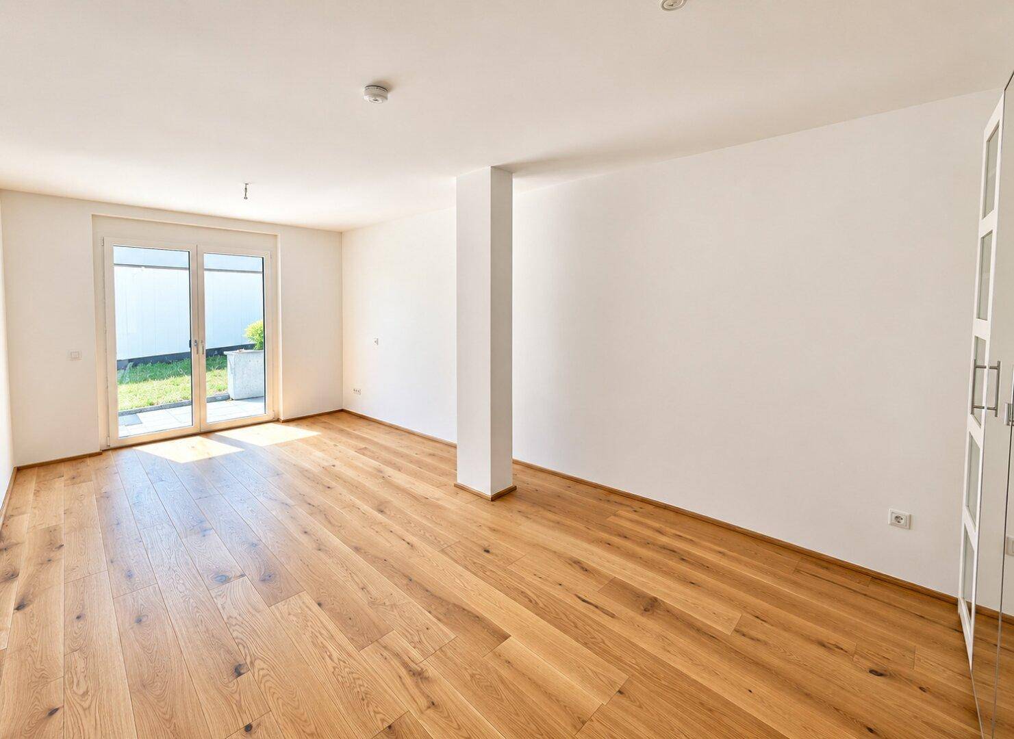 Geräumiges Schlafzimmer mit Holzboden, Einbauschrank und Zugang zu einem Außenbereich.