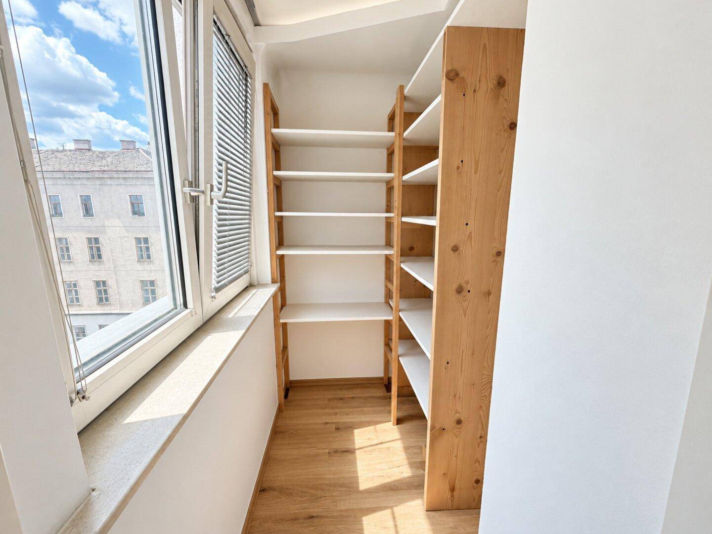 Praktischer Abstellraum mit Holzregalen und einem Fenster, ideal für zusätzlichen Stauraum.