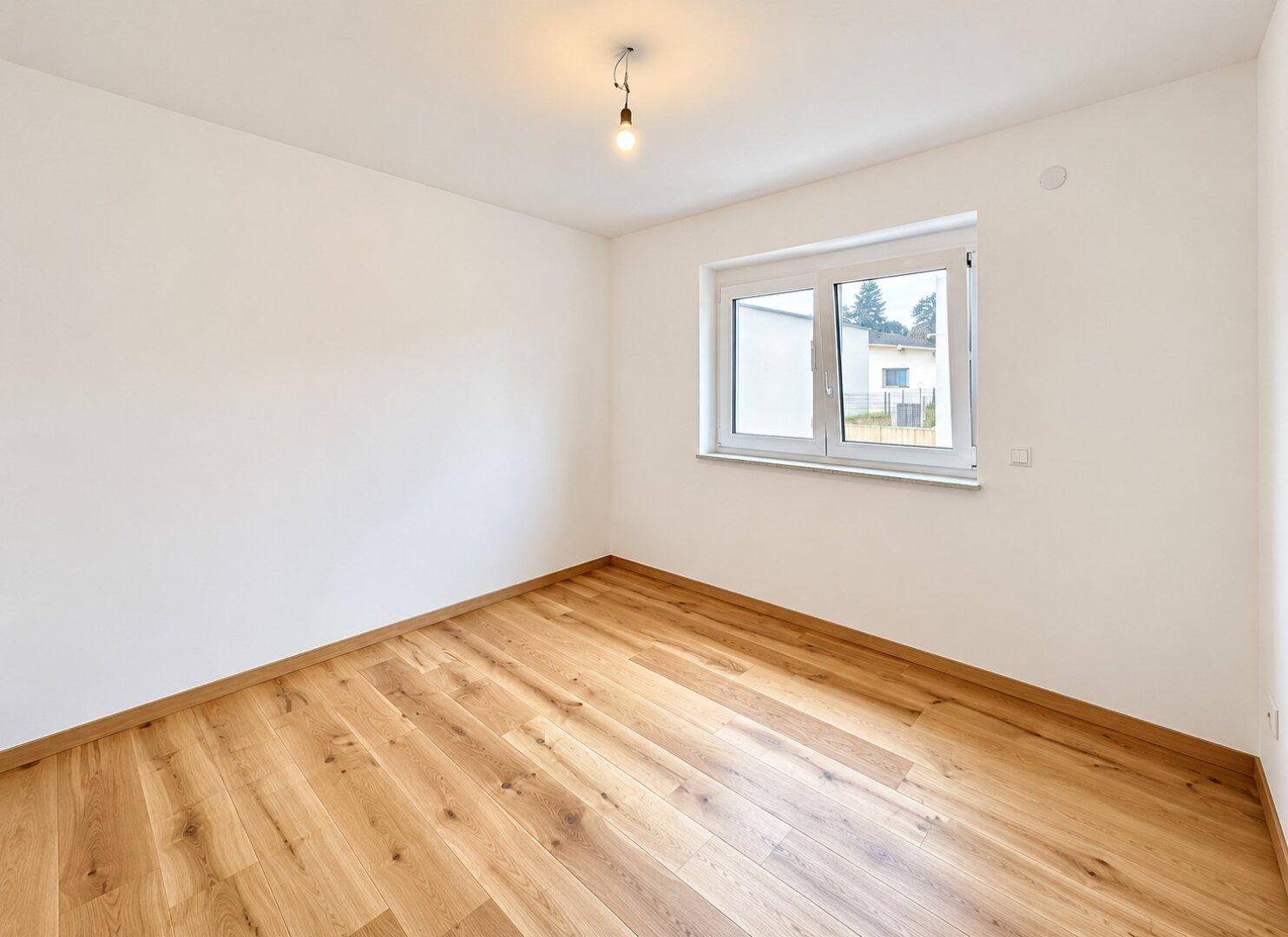 Leeres Zimmer mit Holzboden und Fenster, bietet vielseitige Einrichtungsmöglichkeiten.