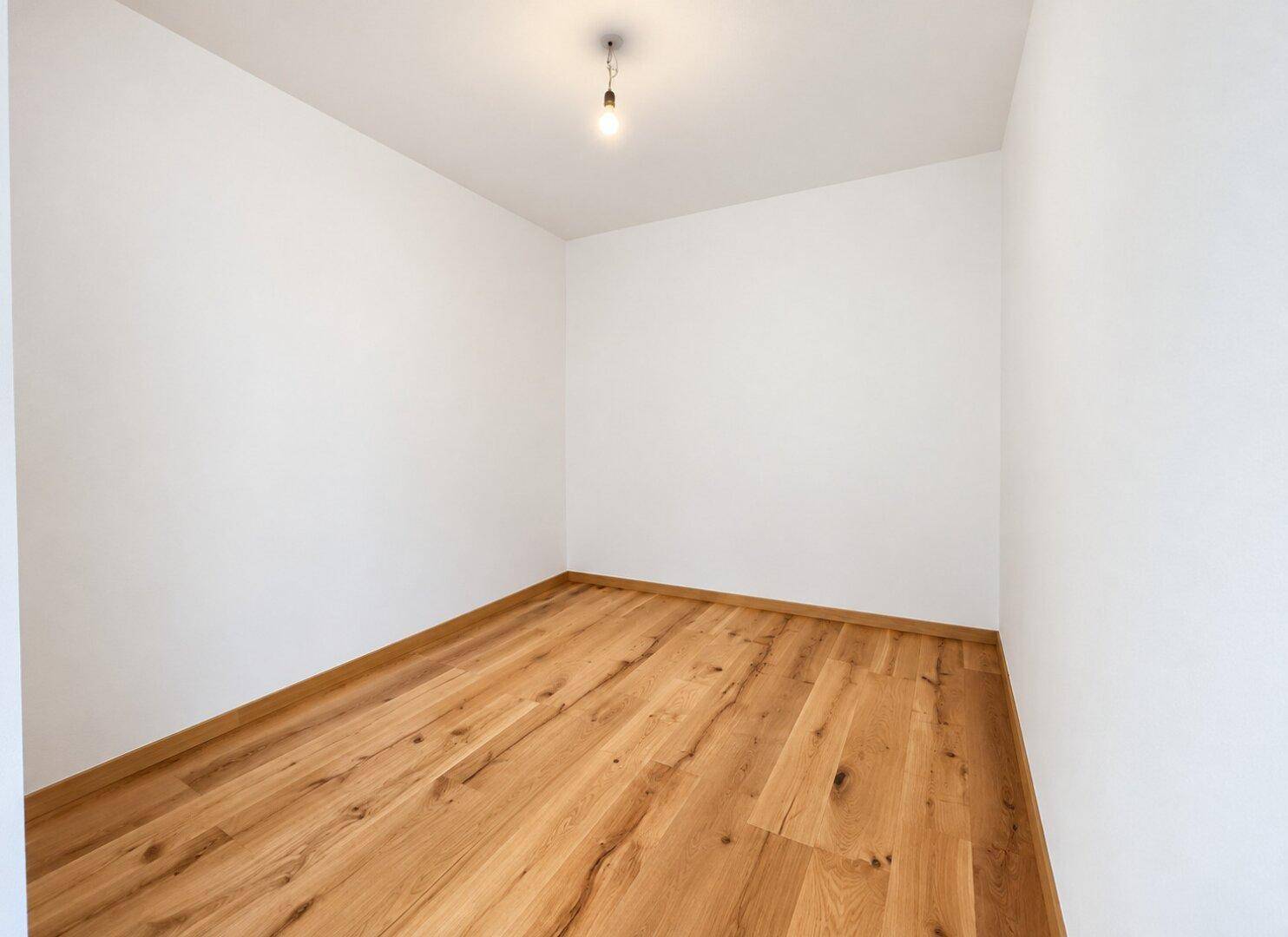 Kleiner, heller Raum mit Holzboden, ideal als Abstellraum oder kleines Büro.