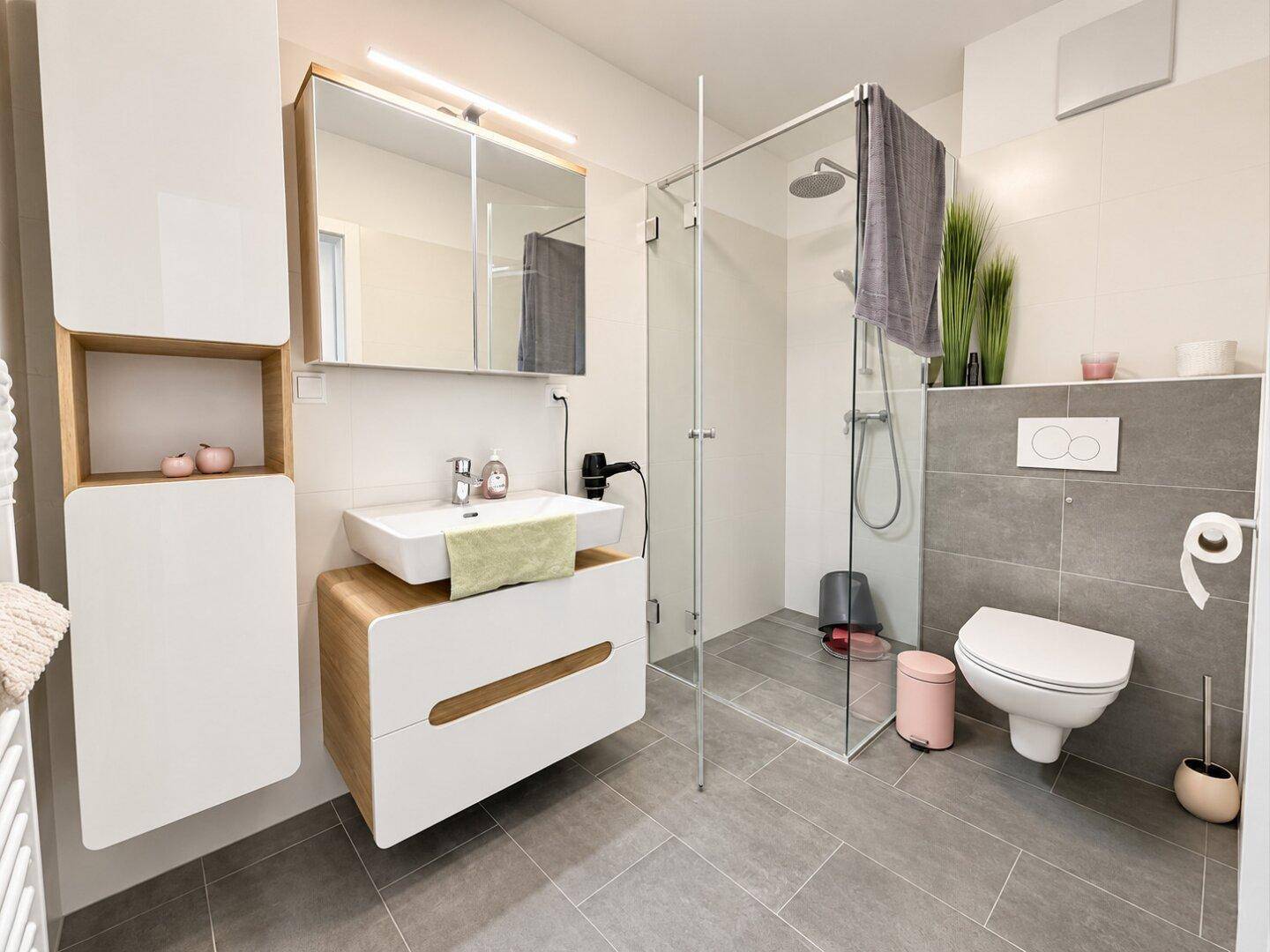 Modernes Badezimmer mit ebenerdiger Dusche, wandhängendem WC und stilvollem Waschtisch.
