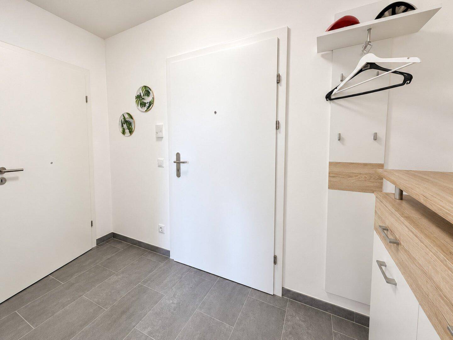 Heller Eingangsbereich mit Fliesenboden und praktischer Garderobe, bietet einen freundlichen Empfang.