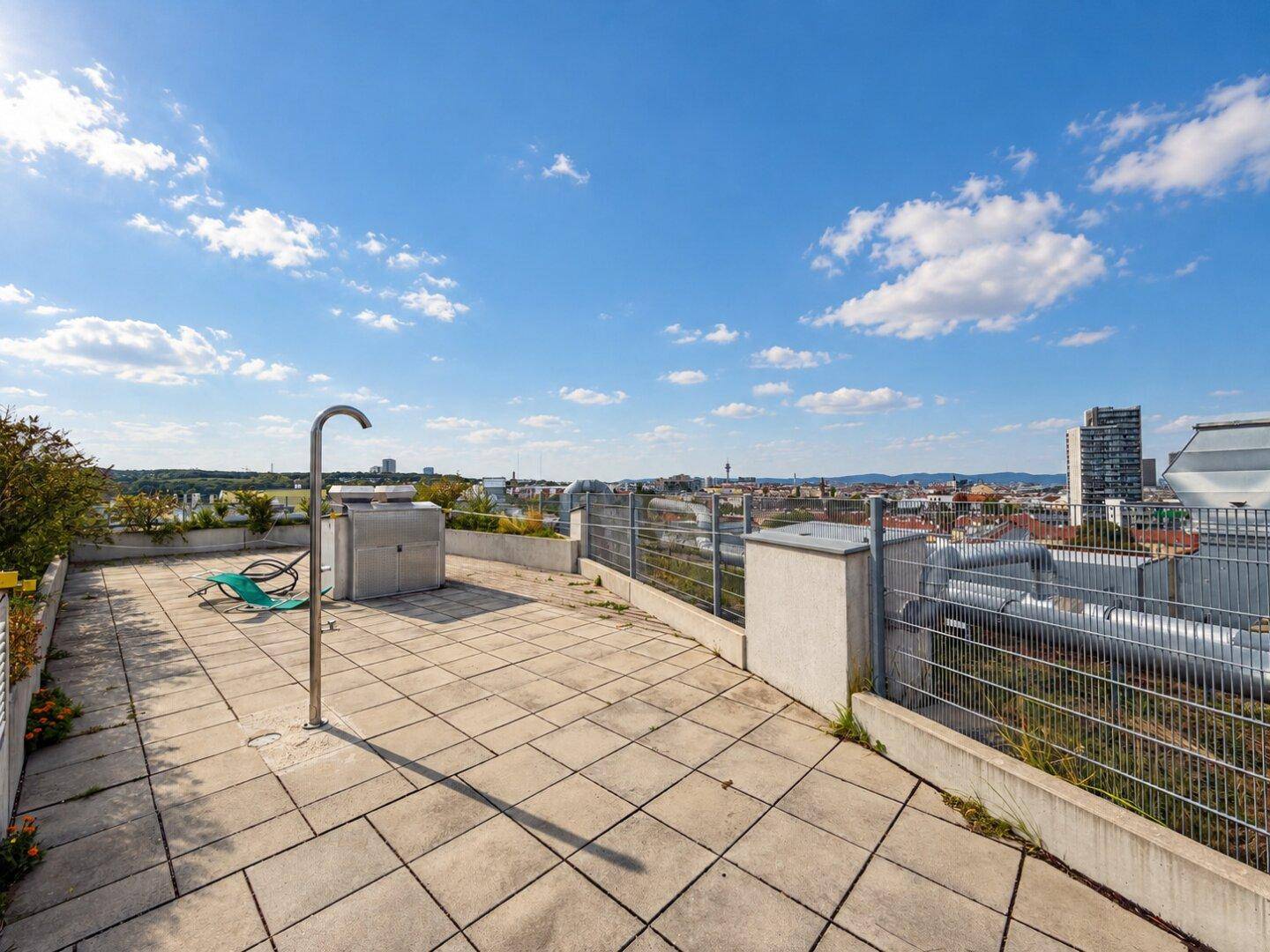 Große Dachterrasse mit Stadtblick, gepflastertem Boden und viel Platz im Freien.