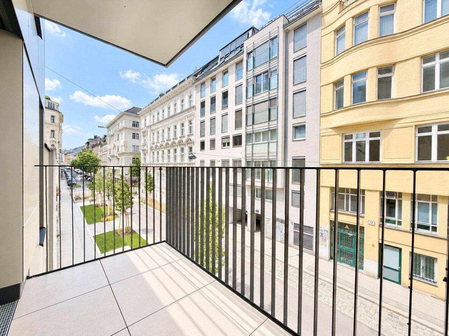 Balkon mit Fliesenboden und Metallgeländer, bietet einen Blick auf die belebte Stadtstraße.