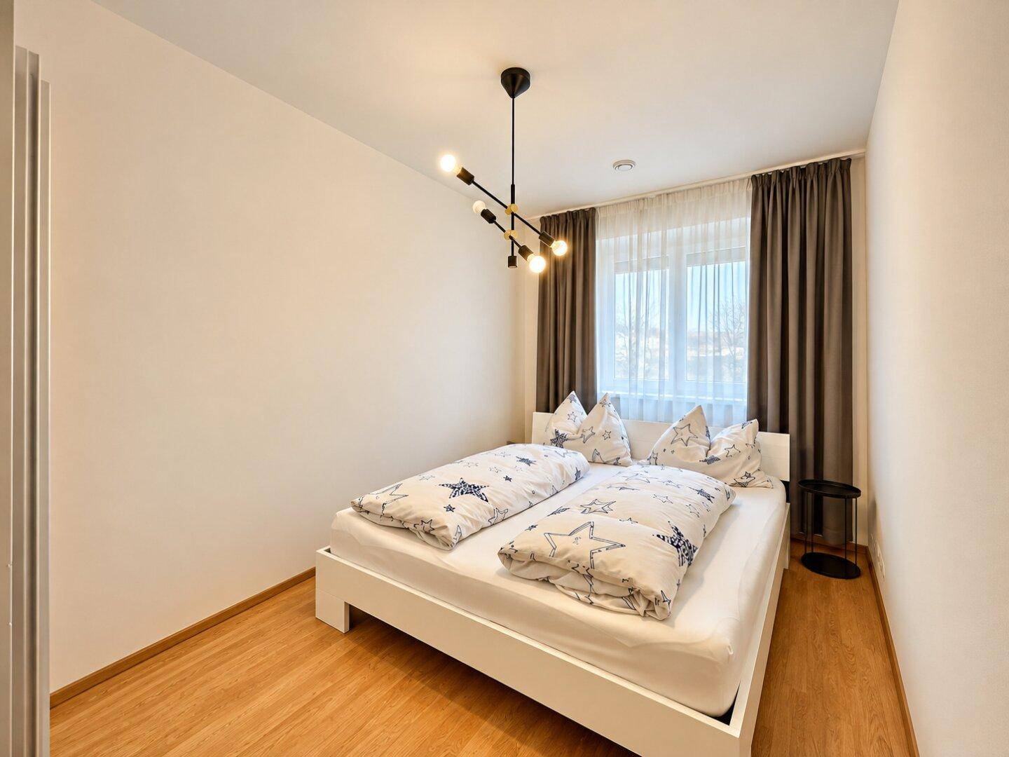Komfortables Schlafzimmer mit weißem Bett und Sternenmuster-Bettwäsche, ideal für erholsamen Schlaf.