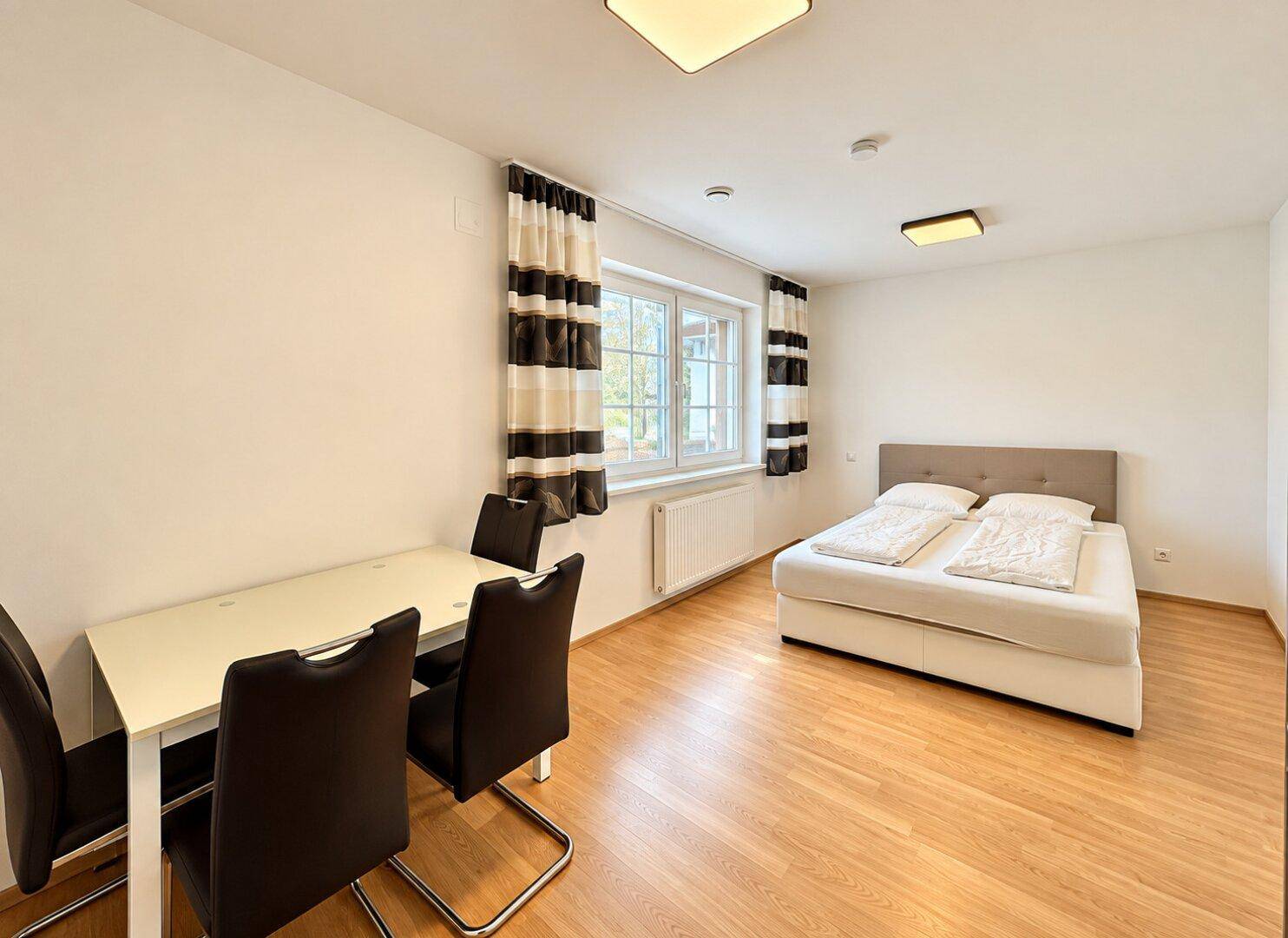 Vielseitiges Zimmer mit Bett und Esstisch, nutzbar als Gästezimmer oder zusätzlicher Wohnraum.