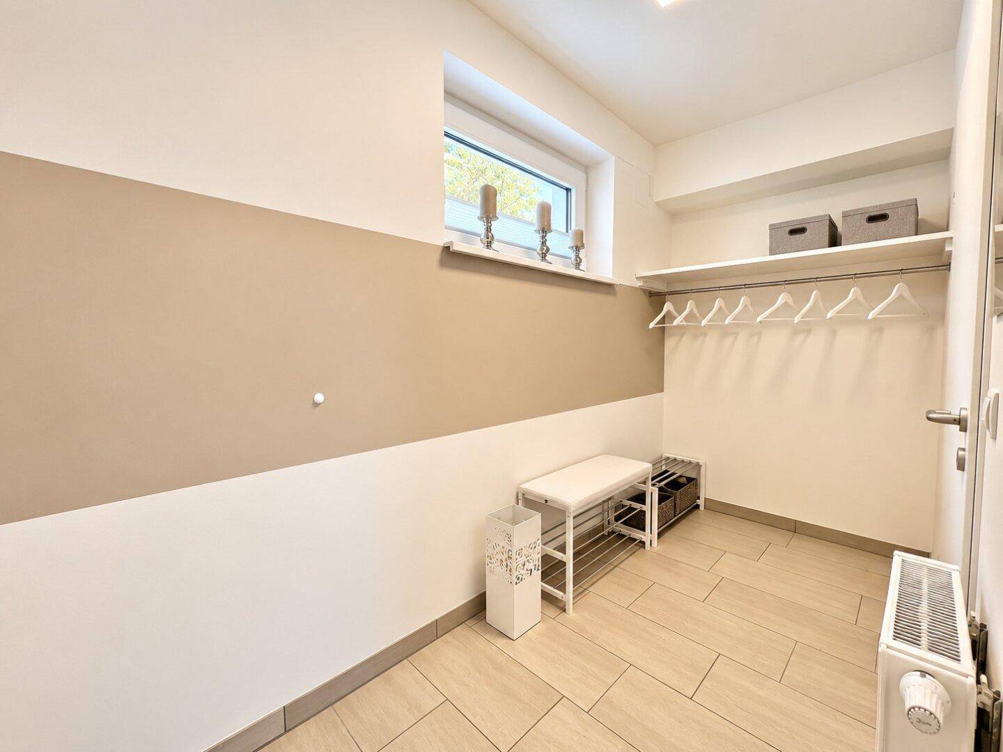 Heller Flur mit Fenster, Sitzbank und Garderobe, bietet praktischen Stauraum und Tageslicht.