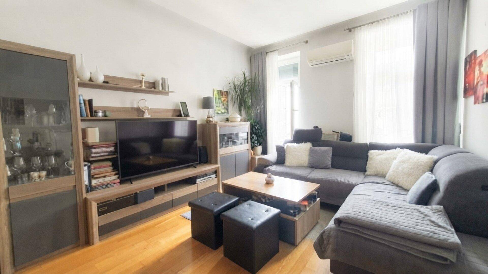 Gemütliches Wohnzimmer mit großem Ecksofa, TV-Möbeln und Holzfußboden.