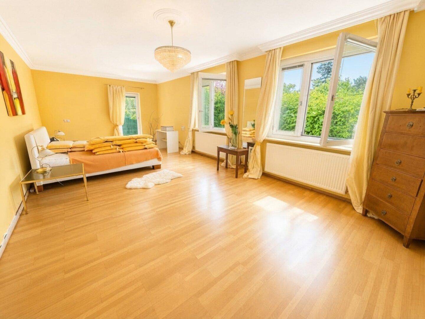 Geräumiges Schlafzimmer mit hellem Holzboden, gelben Wänden und großen Fenstern.