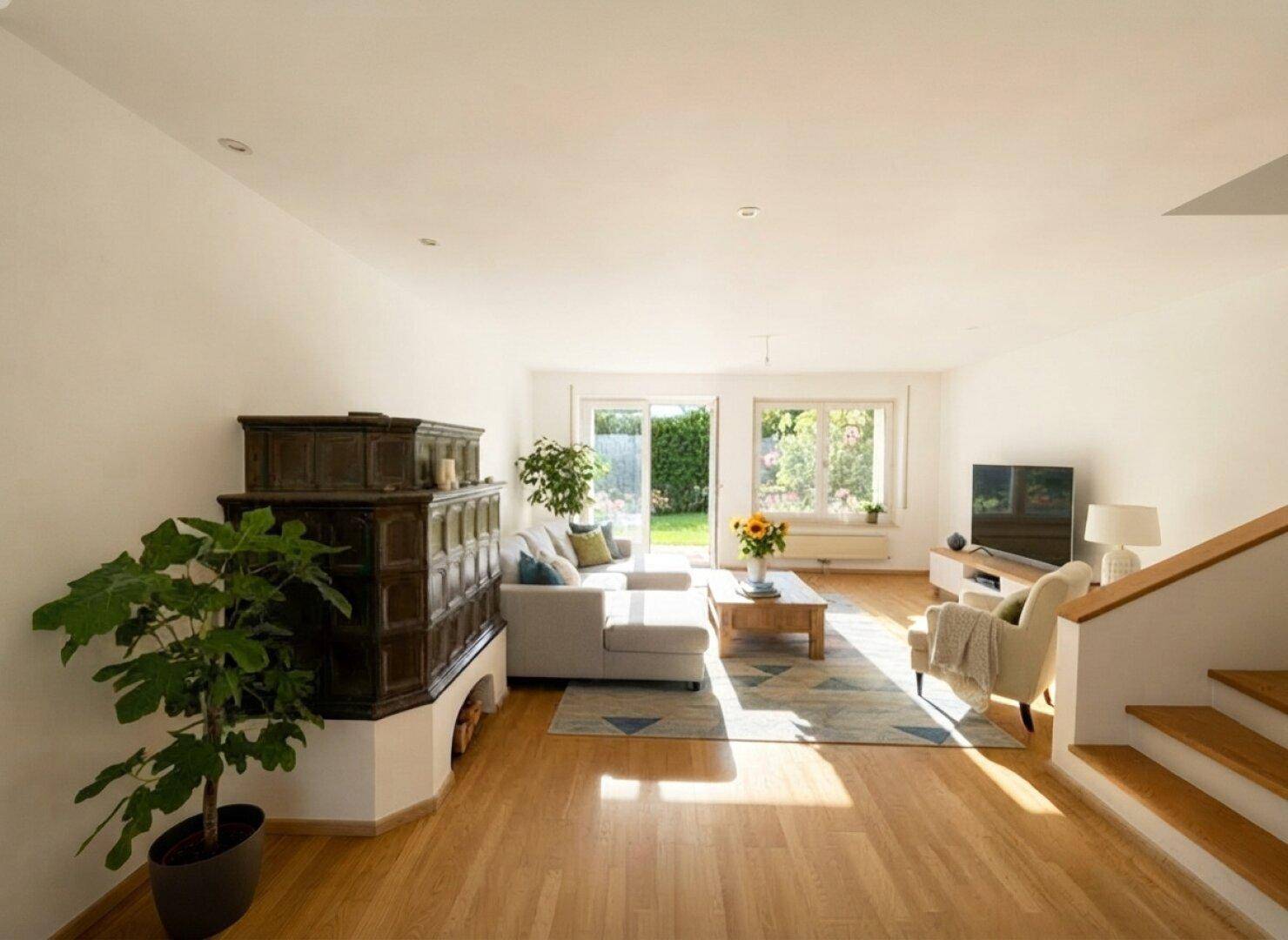 Helles Wohnzimmer mit traditionellem Kachelofen, Parkettboden und direktem Zugang zum Garten.