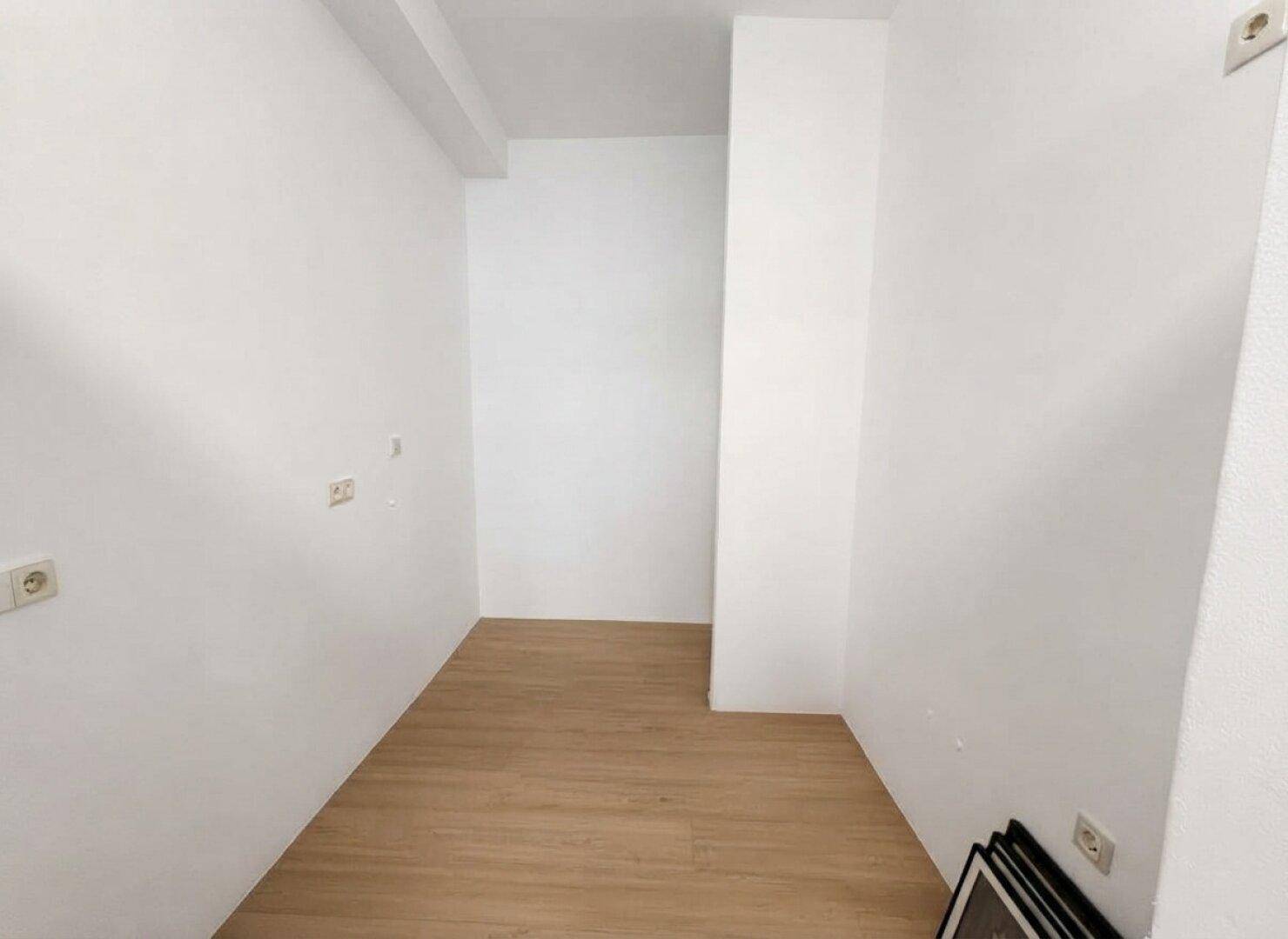 Kleiner, heller Raum mit hellem Holzboden und weißen Wänden, ideal für zusätzlichen Stauraum.
