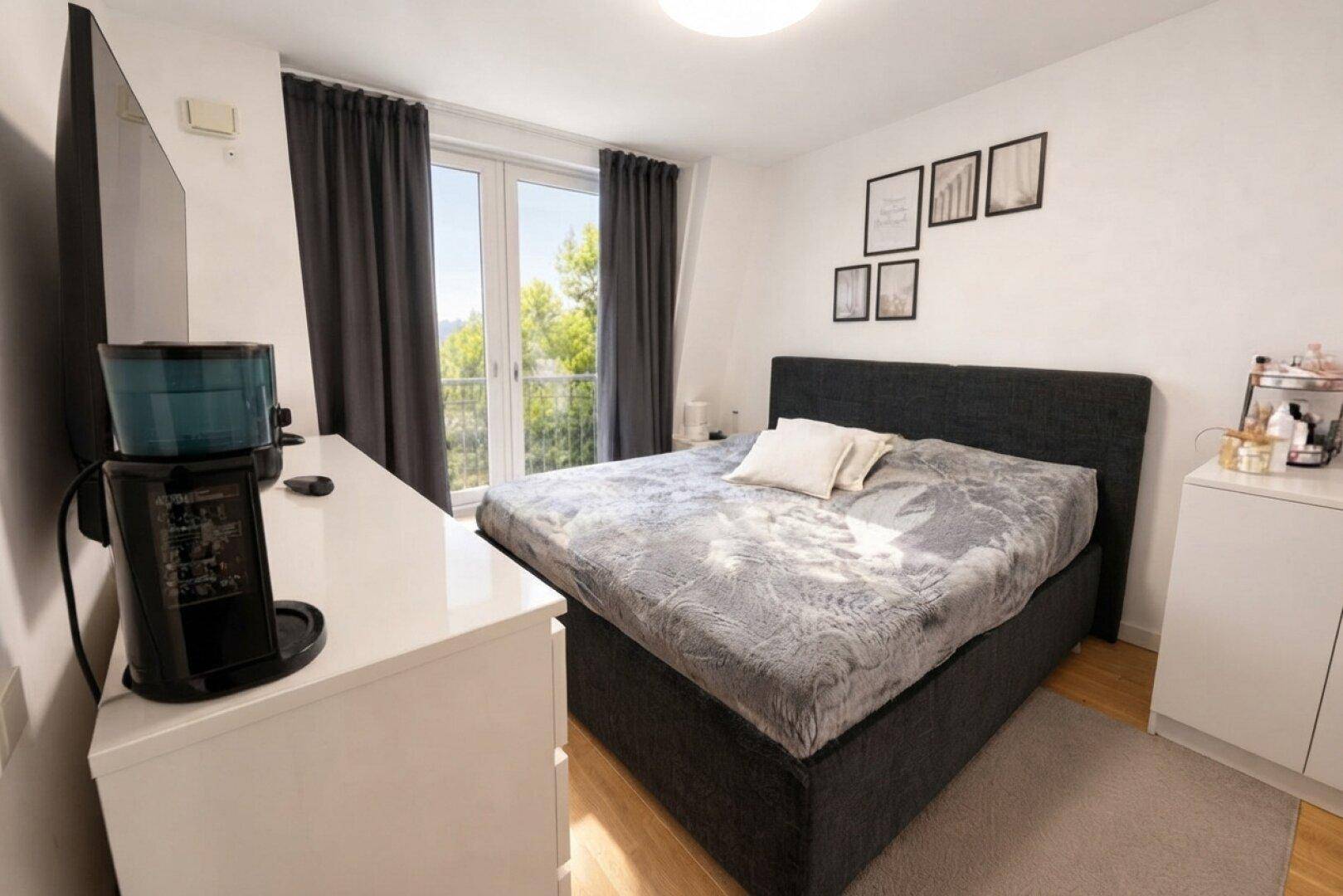 Schlafzimmer mit Doppelbett, Kommode und Zugang zu einem französischen Balkon.
