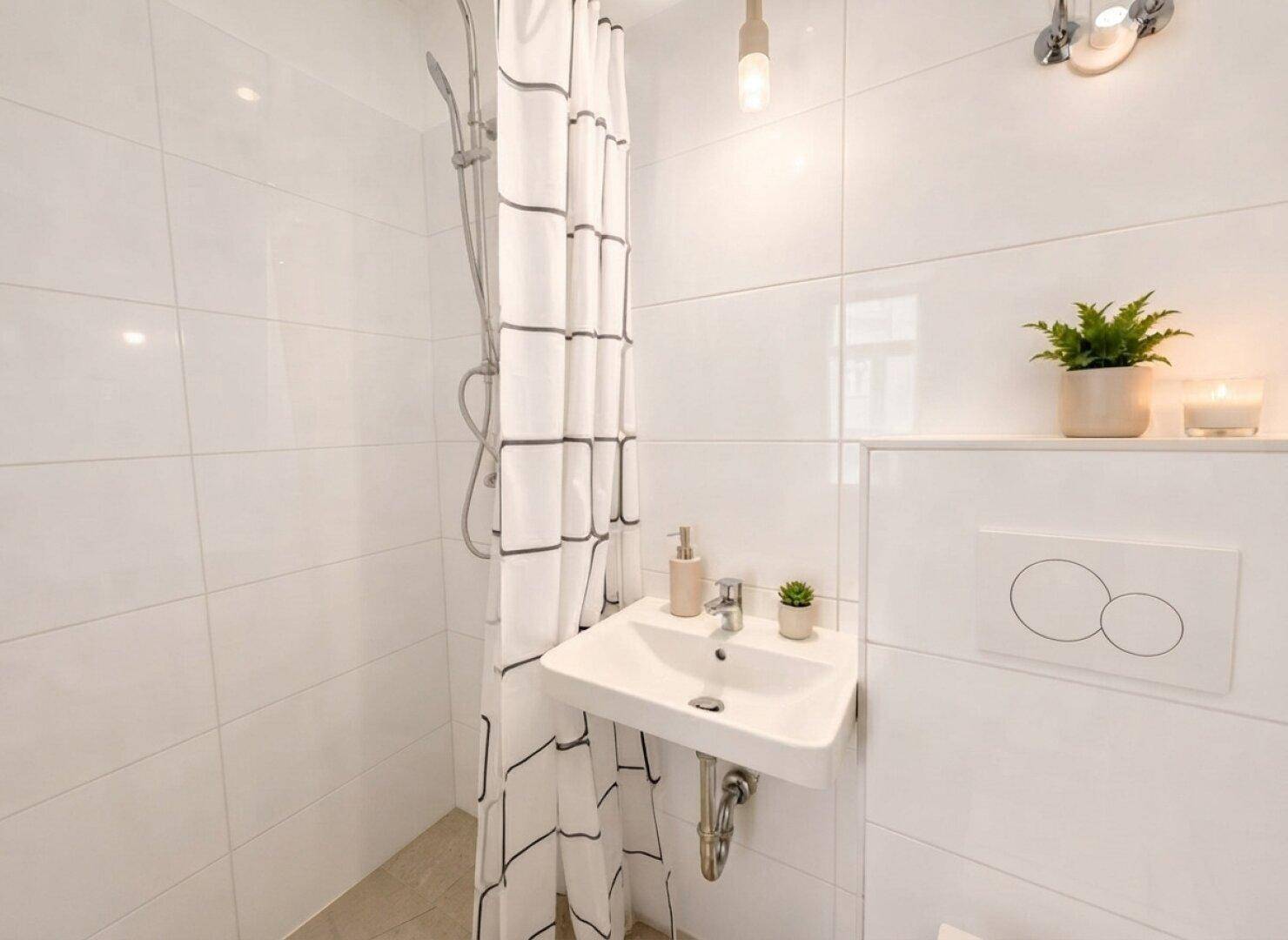 Modernes Badezimmer mit weiß gefliesten Wänden, Dusche, Einzelwaschbecken und Wand-WC.
