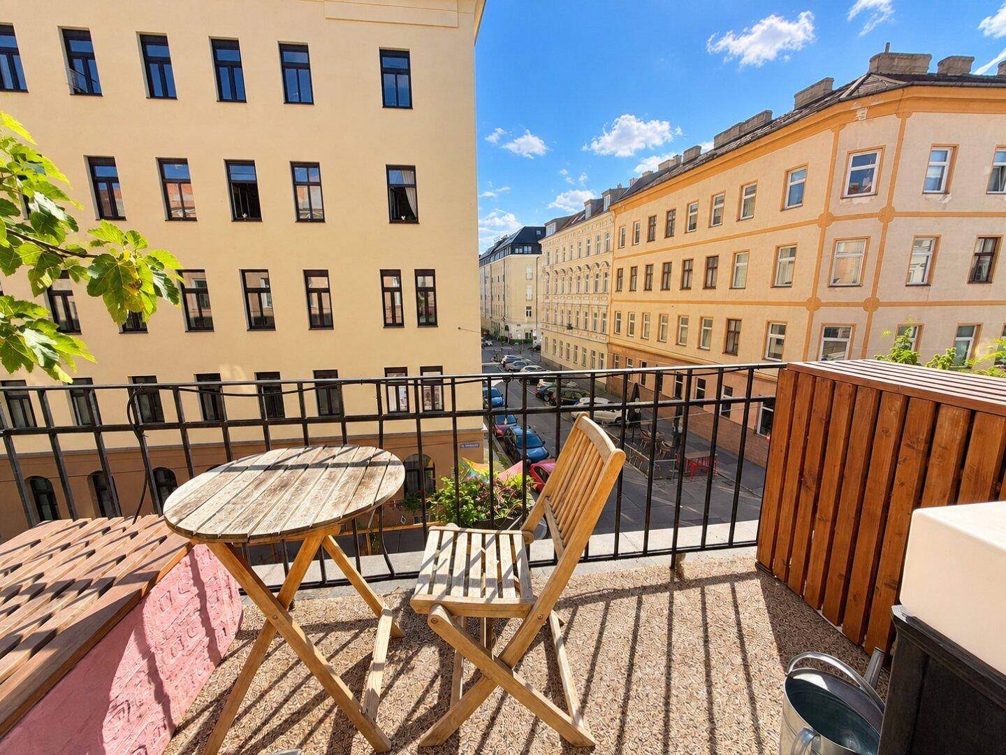Heller Balkon mit gemütlicher Sitzecke und Ausblick auf die belebte Stadtstraße.