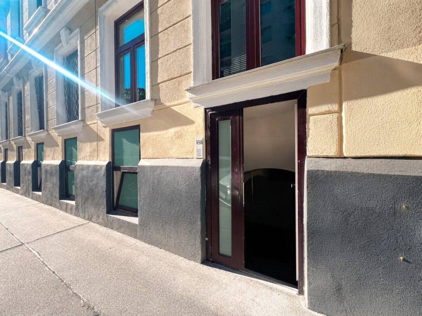 Historische Gebäudefassade mit klassischer Architektur, großen Fenstern und Eingangstür.