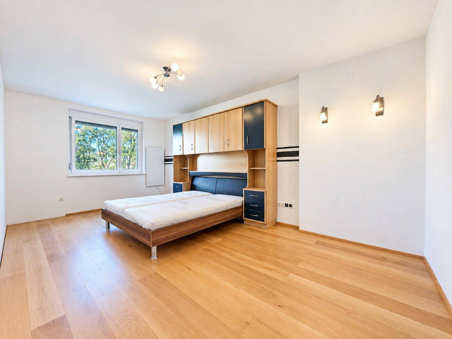Helles Schlafzimmer mit Holzboden, Doppelbett und Einbauschränken, bietet viel Stauraum.