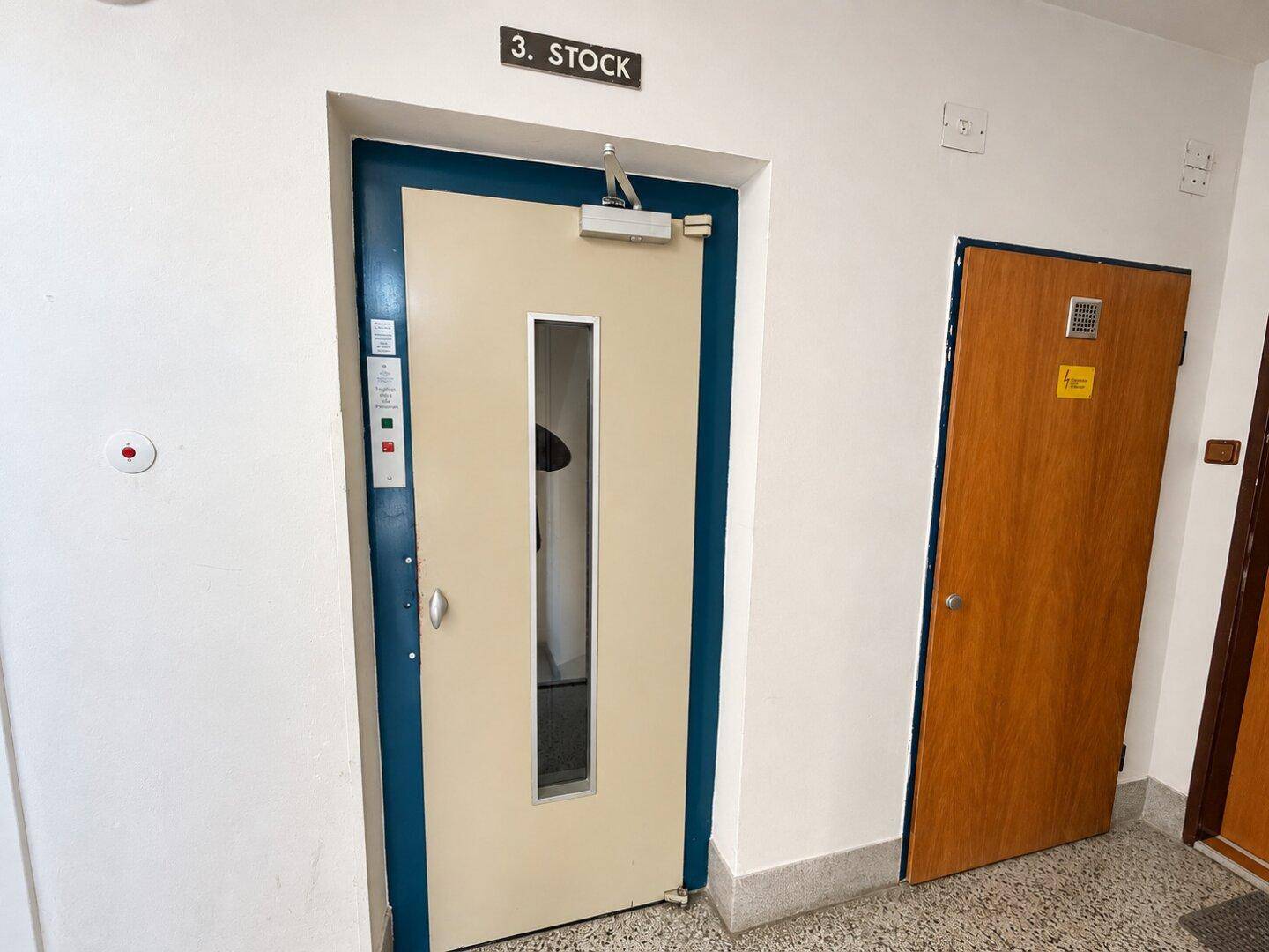 Eingangsbereich eines Gebäudes mit Aufzugstür und Hinweisschild zum dritten Stock.