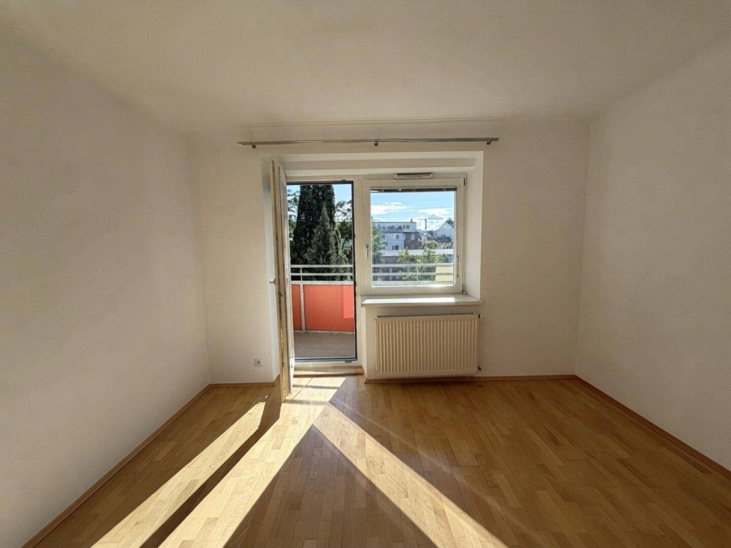 Lichtdurchflutetes Zimmer mit Parkettboden und direktem Zugang zum Außenbereich.