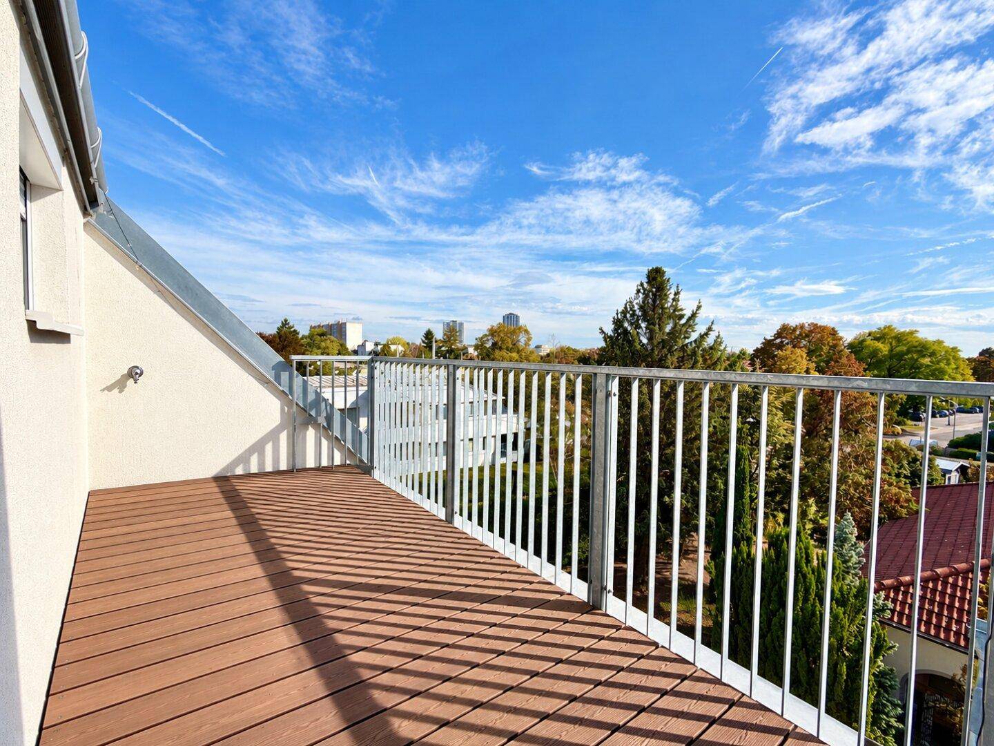 Geräumiger Balkon mit Holzboden und Metallgeländer, bietet einen weiten Blick.