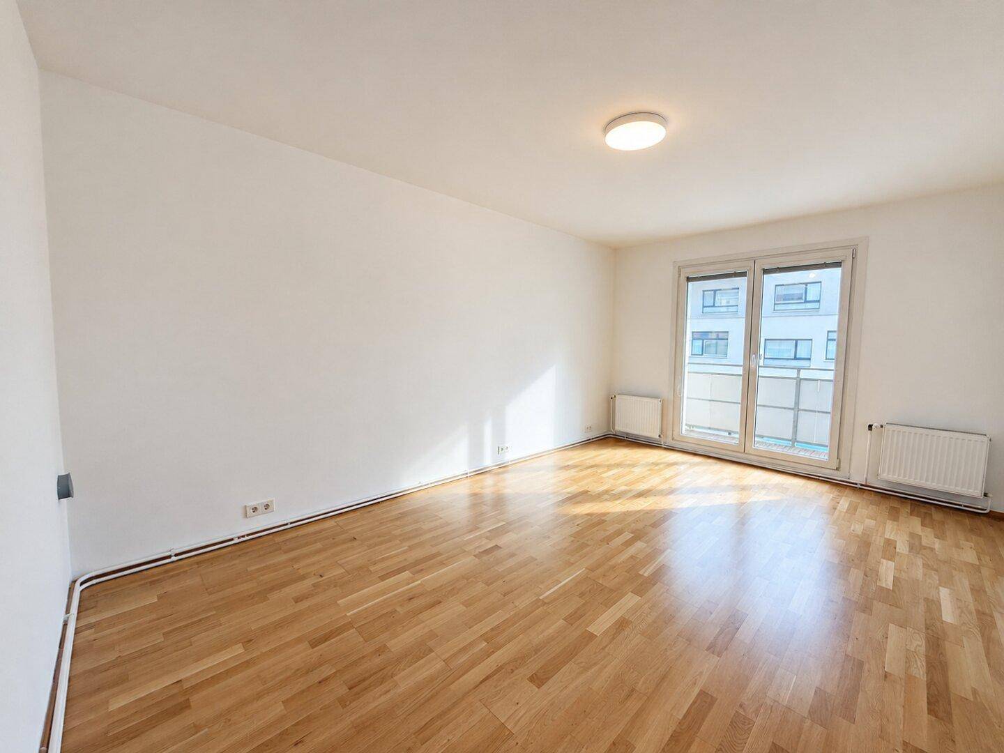 Heller, leerer Raum mit Parkettboden und Zugang zu einem Balkon, ideal für individuelle Gestaltung.