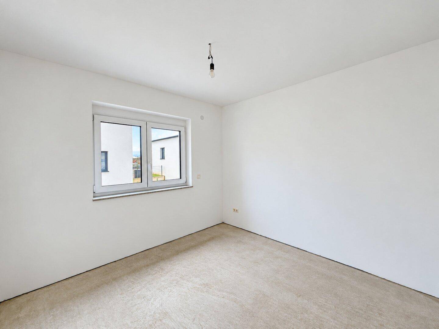 Leerer Raum mit weißen Wänden, Betonboden und Fenster, bereit für die individuelle Gestaltung.