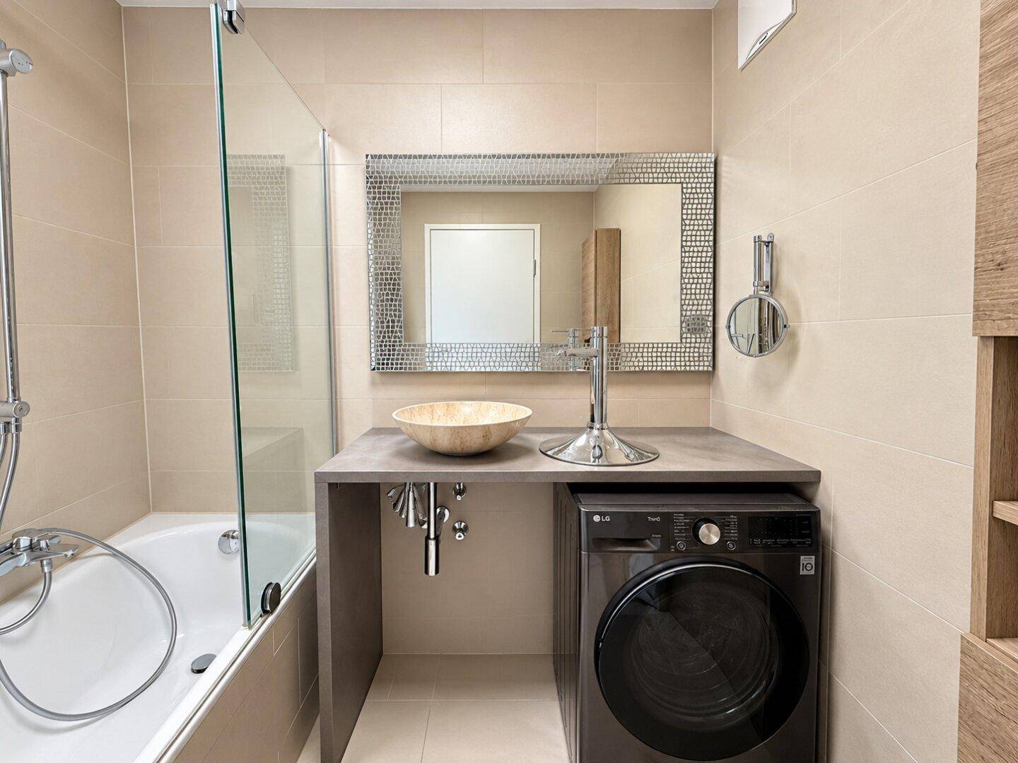 Modernes Badezimmer mit Badewanne, Duschabtrennung und integrierter Waschmaschine unter dem Waschtisch.