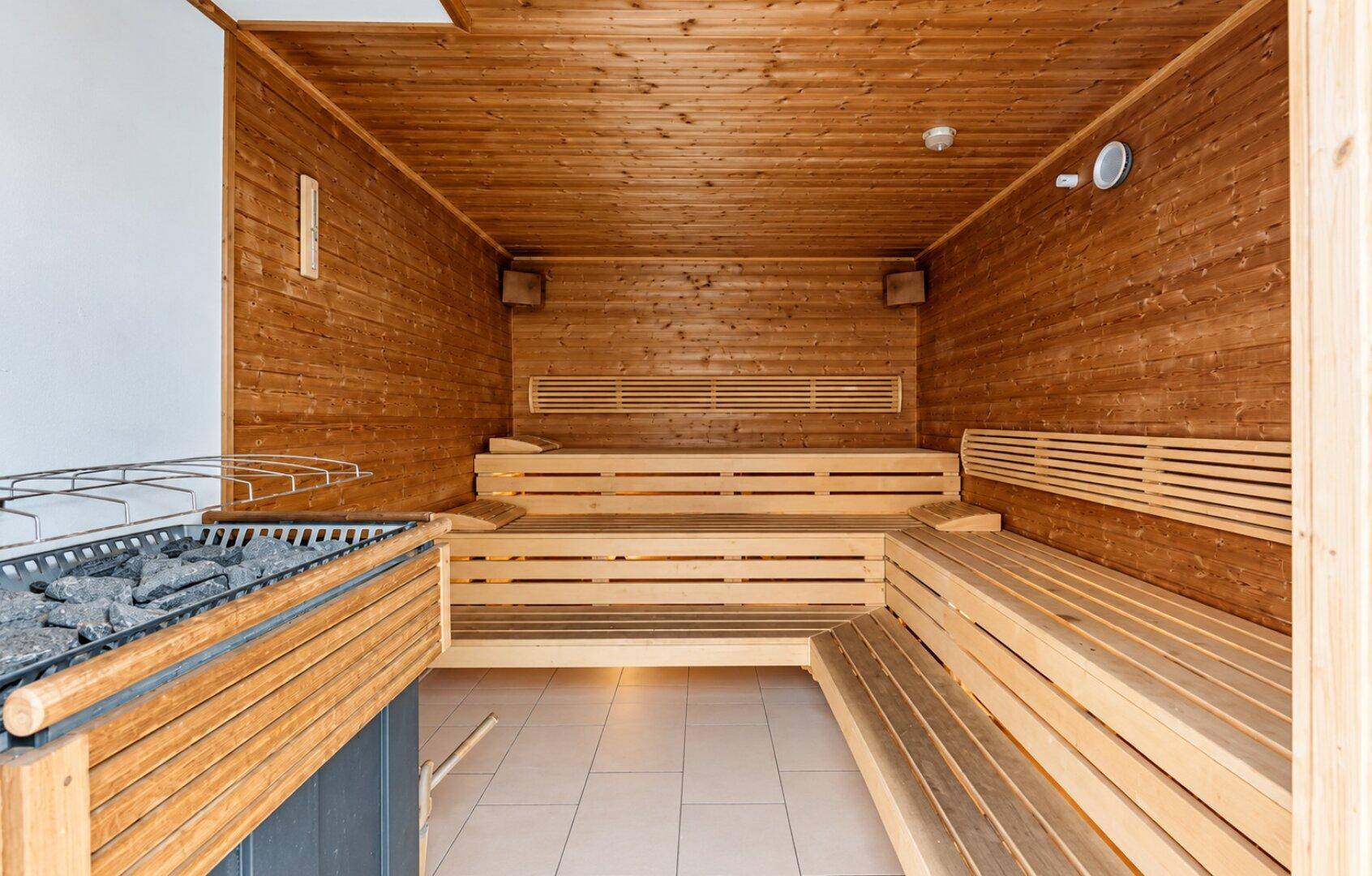 Traditionelle Holzsauna mit mehreren Bänken und einem Saunaofen, bereit zur Entspannung.