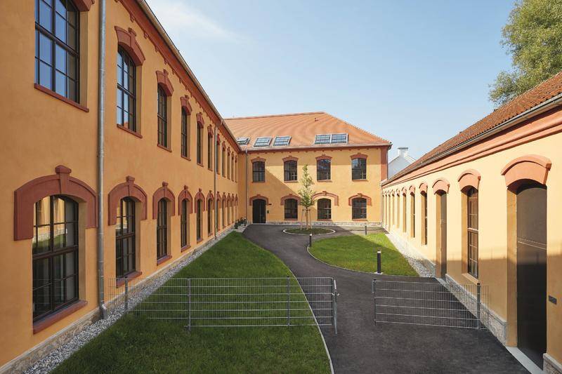 Innenhof des Studentenwohnheims mit gepflegtem Rasen, Gehwegen und der historischen Gebäudefassade.