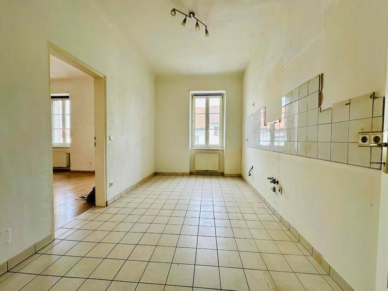 Leere Küche mit Fliesenboden und Wandfliesen, bereit für die Installation einer neuen Einbauküche.